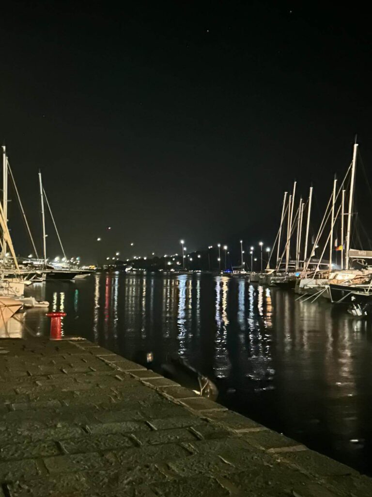 Vista notturna del porto di Santa Marina Salina, Eolie, con barche ormeggiate illuminate.