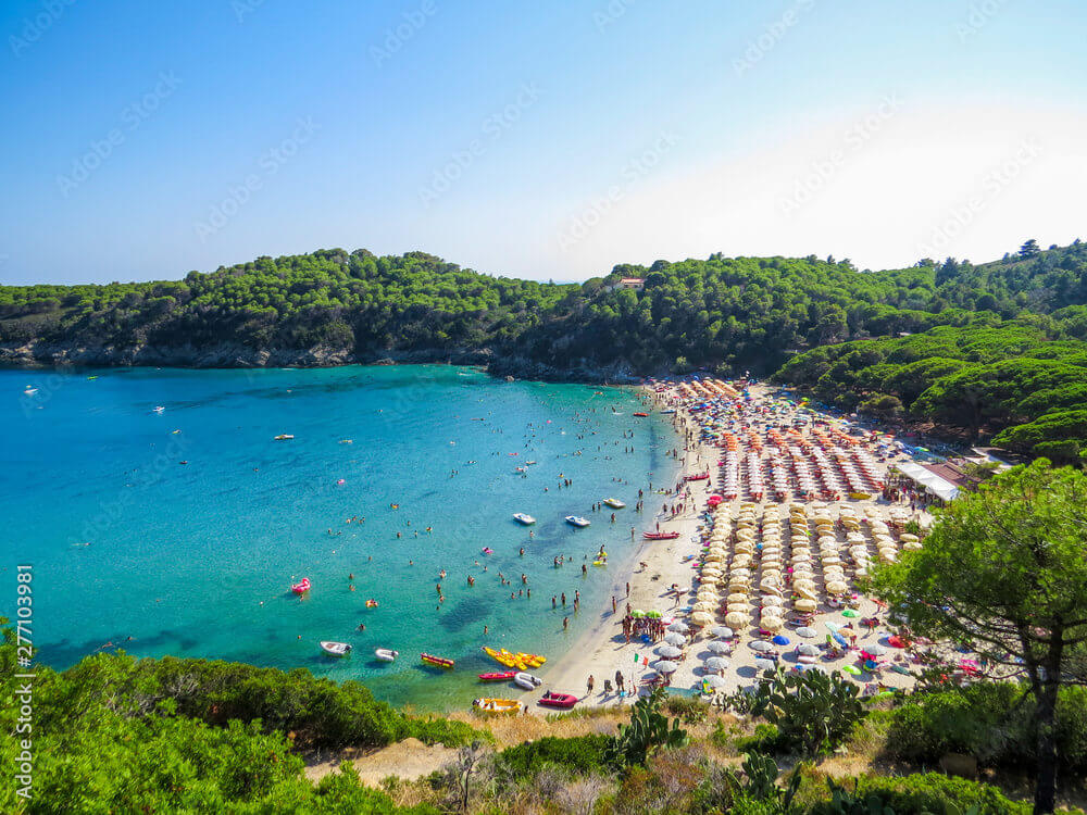 Mezzaluna di sabbia dorata e scogliere granitiche a Fetovaia, Isola d'Elba, con acque trasparenti color turchese.