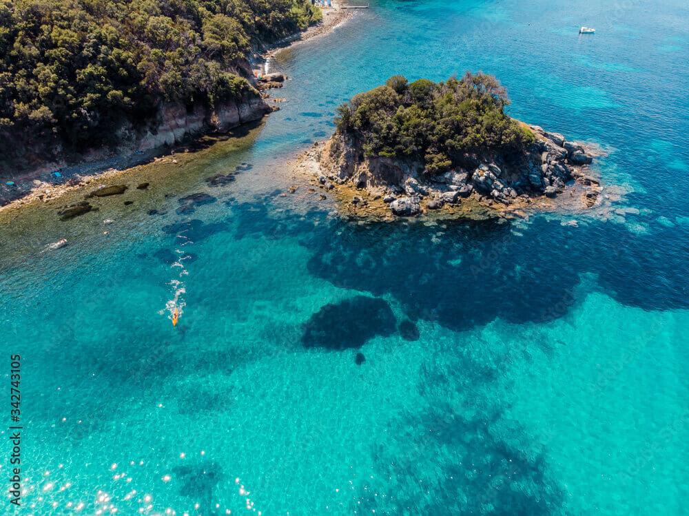 Suggestiva Isola Paolina all'Elba, un piccolo isolotto roccioso circondato da acque turchesi, ideale per snorkeling durante una crociera in catamarano.