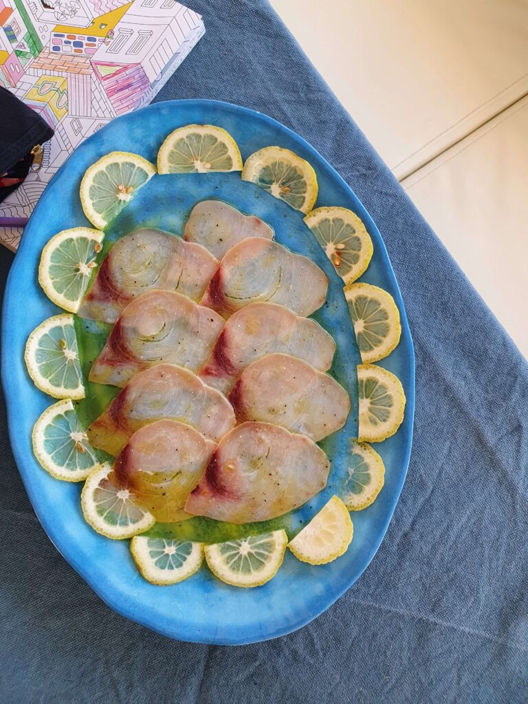 Fettine di pesce spada marinato, piatto leggero e gustoso, preparato fresco a bordo di una barca a vela per una crociera indimenticabile.